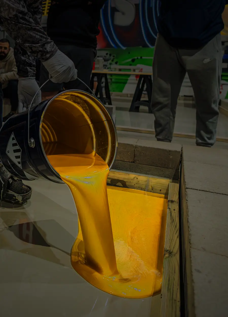 Gold metallic epoxy pours from a bucket onto a training floor