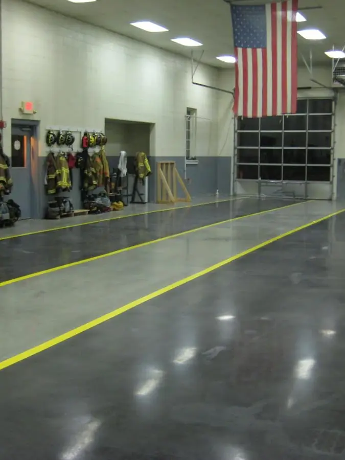 Solid grey epoxy floor with yellow safety striping in a fire station