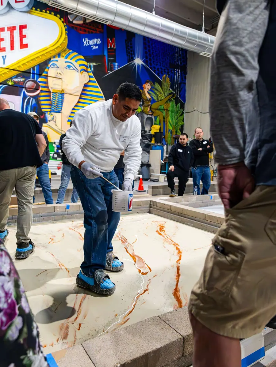 A student pours a marble style metallic epoxy floor during class