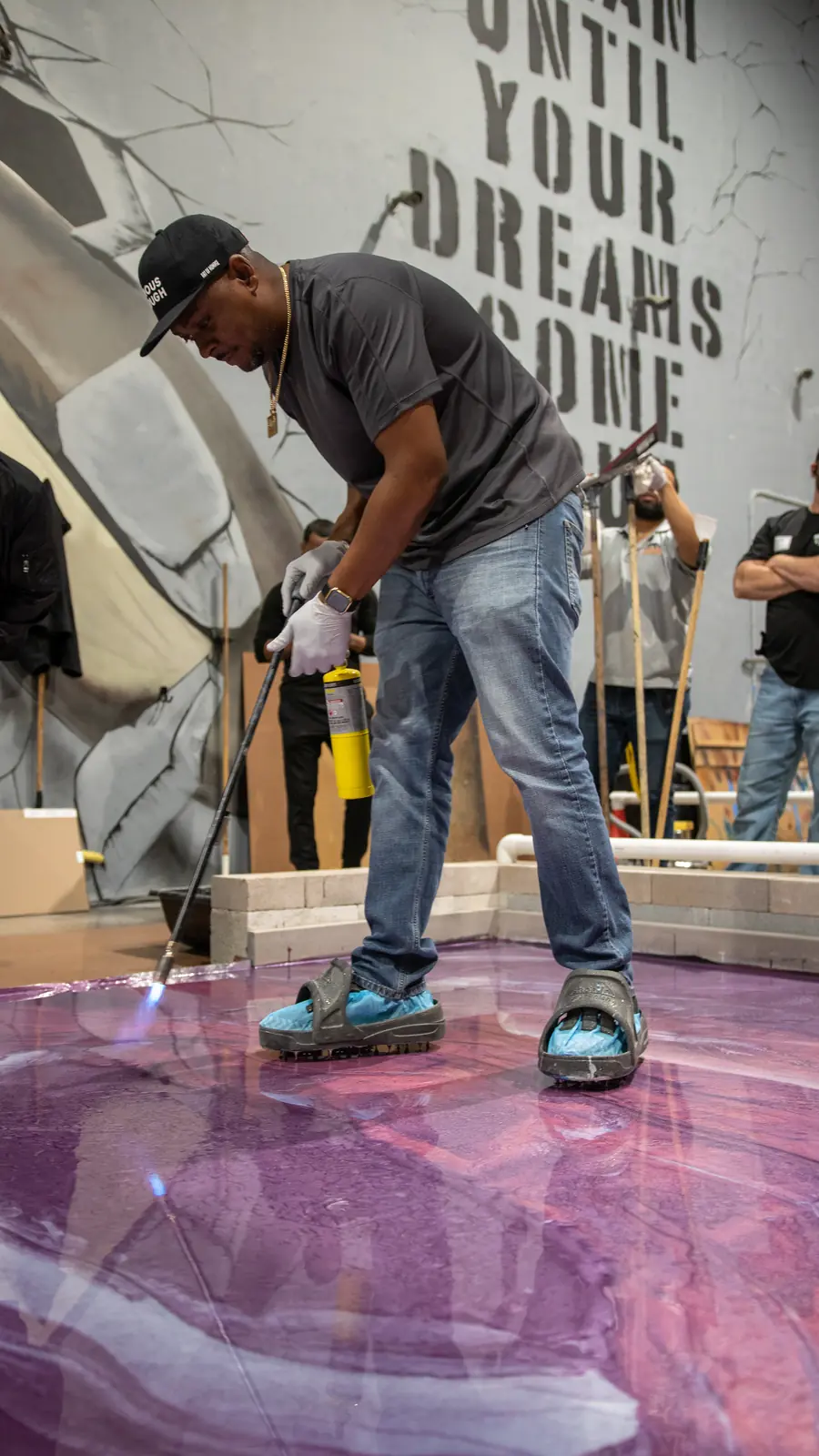 A student finishes a purple metallic epoxy floor in the training bay