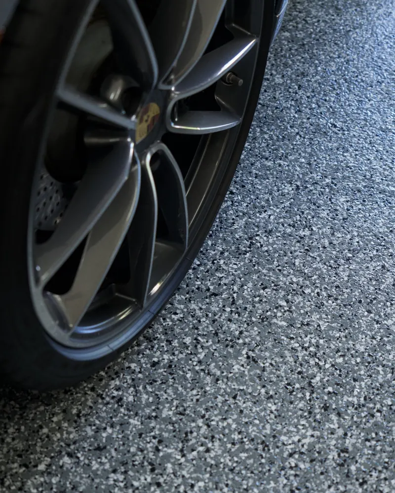 Blue and grey decorative flake floor under a car wheel