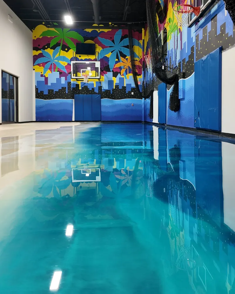 Glossy teal metallic epoxy floor in an indoor basketball court