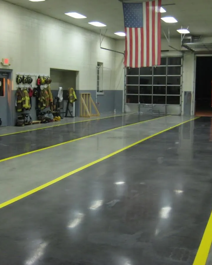 Grey solid color epoxy floor with yellow safety striping in a fire station